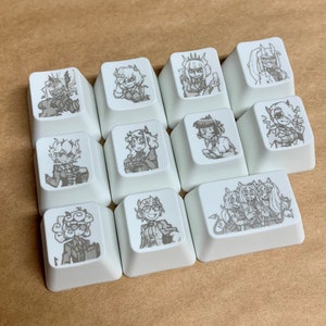 May include: Twelve white keycaps with black and white illustrations of various characters. The keycaps are arranged in a grid pattern.