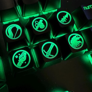 May include: Close-up of a gaming keyboard with illuminated green keycaps. The keycaps feature various symbols and icons, including a pickaxe, a bag of coins, and other game-related graphics. The keyboard is designed for gaming.
