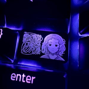 May include: A keyboard keycap with a black background and a white design. The design features a drawing of a person with short hair and text that says "Made for the love of the game". The keycap is illuminated with a purple light.