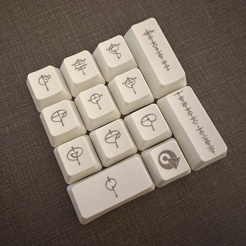 May include: A set of 12 white keycaps with various symbols and text, including "Adventure is Out There" and "How do you do, fellow kids?"