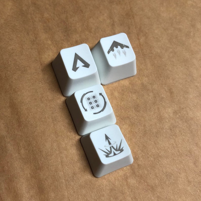 May include: Four white keyboard keycaps with different symbols. The keycaps feature a triangle, a plane with smoke trails, a circle with nine dots, and an arrow with a circle around it.