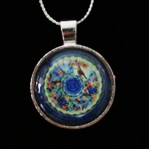 May include: A silver chain necklace with a round pendant featuring a blue and white floral design with a small red bird.