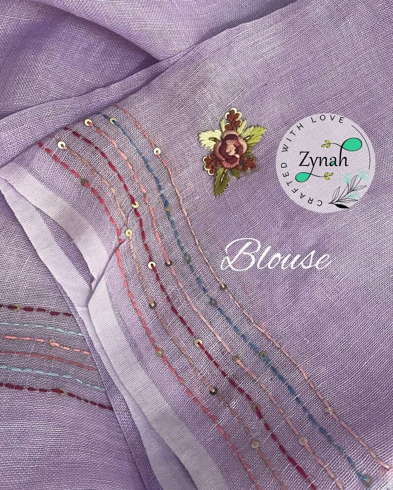 May include: A lavender blouse with a white trim and embroidered details. The trim features a row of gold sequins and colorful stitching. The embroidery includes a floral design and the text "Crafted with Love Zynah".
