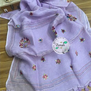May include: A lavender linen scarf with embroidered floral designs and a white border. The scarf has a fringe trim and the text "Crafted with Love Zynah" is embroidered on the scarf.