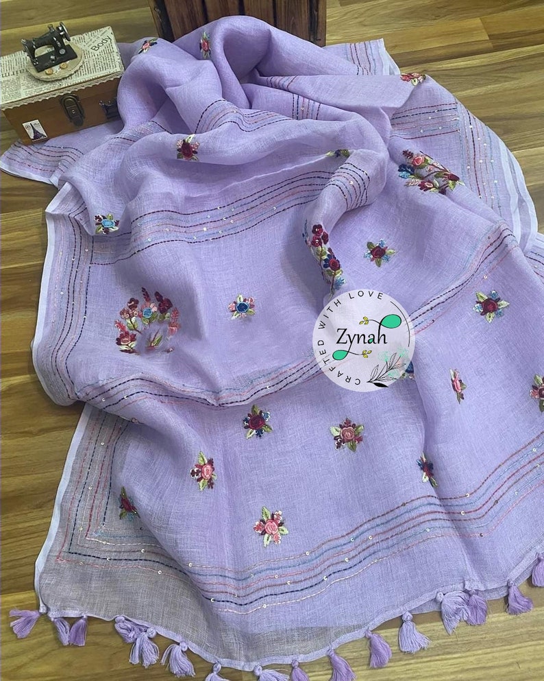 May include: A lavender linen scarf with embroidered floral designs and a white border. The scarf has a fringe trim and the text "Crafted with Love Zynah" is embroidered on the scarf.