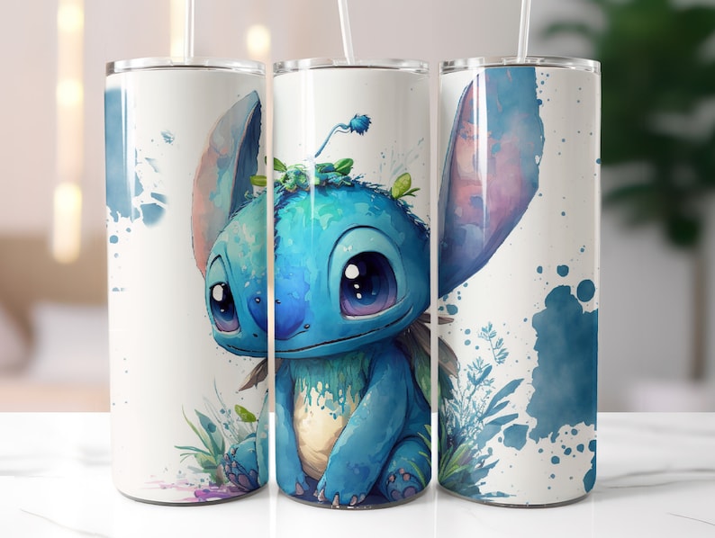 May include: A white stainless steel tumbler with a blue and green watercolor illustration of Stitch from Lilo & Stitch. The tumbler has a straw and a lid.