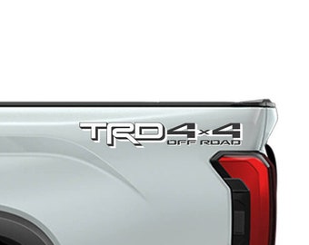 May include: A silver pickup truck with a black "TRD 4x4 OFF ROAD" decal on the side. The truck has a black wheel with a silver rim.