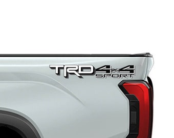 May include: A silver pickup truck with a black "TRD Sport 4x4" decal on the side of the truck bed.