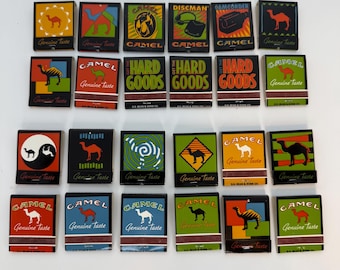 May include: A collection of vintage Camel matchbooks, featuring various designs with the Camel logo and text. The matchbooks display a range of colors, including red, green, and black, with the words "Genuine Taste" on some.