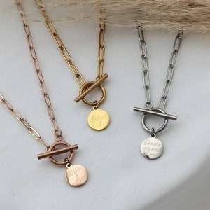 May include: Three gold, silver and rose gold necklaces with personalised engraved round pendants. Each necklace features a toggle clasp.