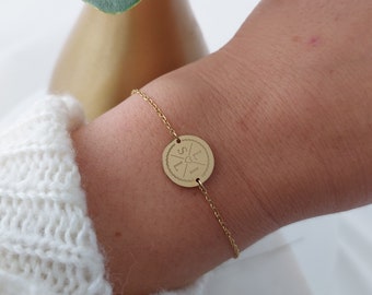 Op de afbeelding: Een gouden kettingarmband met een ronde bedel met de letters "L" en "S" gescheiden door een hartje.
