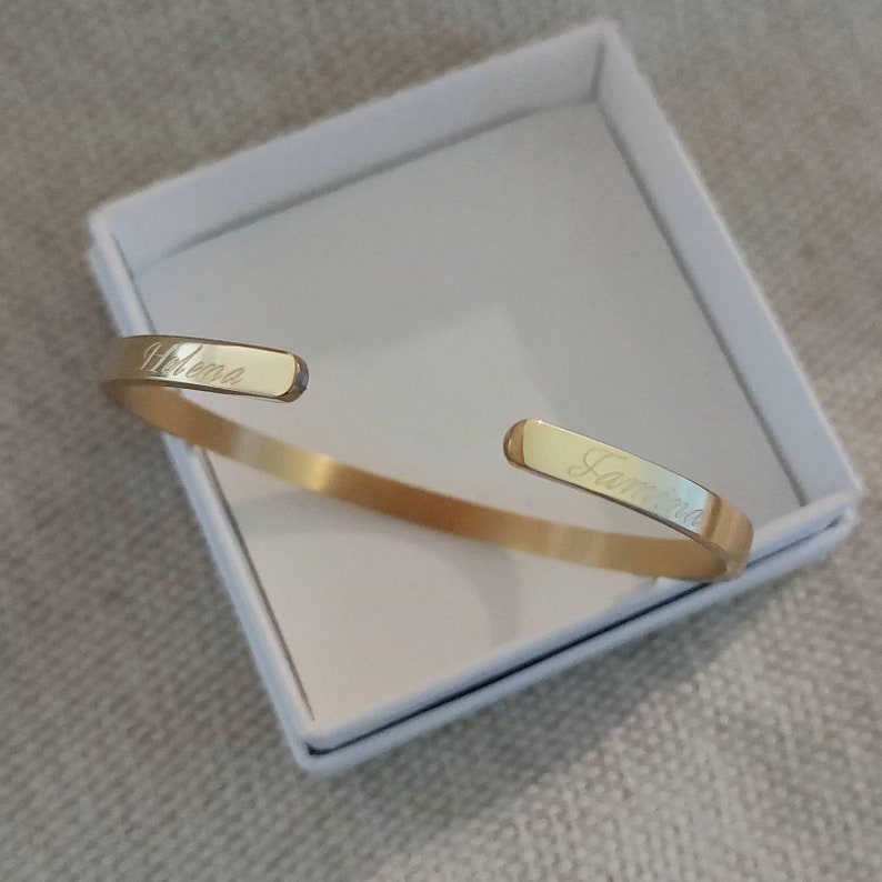 Op de afbeelding: Gouden armband met de namen "Helena" en "Tamara" gegraveerd.