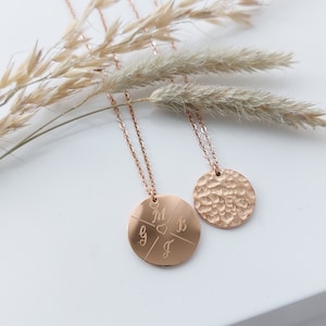 May include: Two gold necklaces with round pendants. One pendant has a hammered texture, the other has four initials and a heart engraved on it.