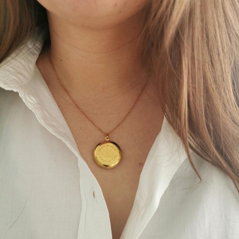 May include: A gold chain necklace with a round gold locket pendant.
