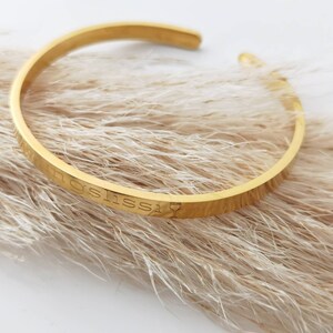 Op de afbeelding: Gouden armband met de inscriptie "I'm a little obsessed" en een wijnglasicoon.