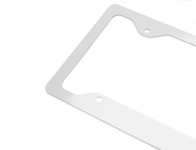 Puede incluir: Un marco rectangular para matr&iacute;cula de metal color plateado con un acabado liso y reflectante. El marco cuenta con dos orificios de montaje circulares situados en el borde superior y dos orificios circulares en el borde inferior.