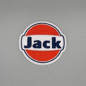 May include: A red and white embroidered patch with the word "Jack" in blue lettering. The patch is circular and has a white border.