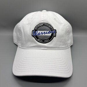 May include: White baseball cap with a black and white embroidered logo that says "Oconee County Warriors Est. 1957".