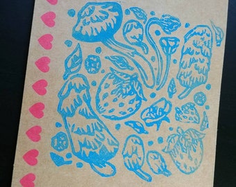 May include: A brown card with a blue ink stamp design featuring mushrooms, strawberries, and flowers. A row of pink hearts is along the left edge of the card.