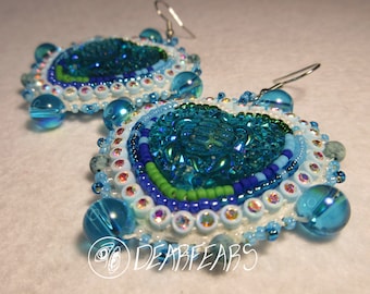 May include: A pair of blue and white beaded earrings with a turquoise center piece. The earrings are handmade and feature a variety of beads, including iridescent glass beads and seed beads.