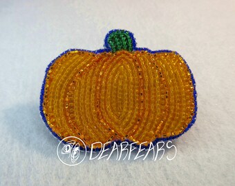 May include: A beaded pumpkin with a green stem and blue outline. The pumpkin is made of small, round beads in shades of orange and yellow.