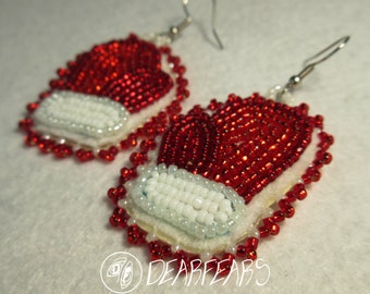 May include: Red and white beaded earrings shaped like mittens. The earrings are made with small, red beads and white beads. The earrings are attached to silver hooks.