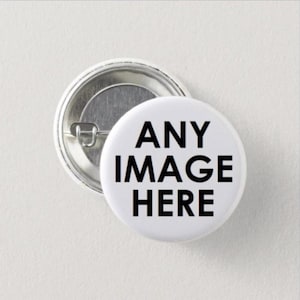 May include: A round pin-back button with a white surface featuring the black text ANY IMAGE HERE. The back of the button is metallic silver with a pin mechanism visible, showing the construction of the circular accessory.
