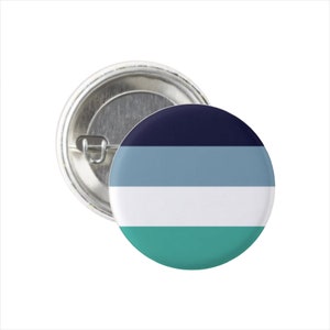 May include: A round button pin with a silver metal backing. The button features a design of horizontal stripes in navy blue, light blue, white, and teal. The pin is a simple, yet eye-catching accessory.