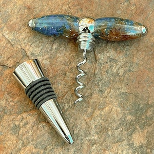 Può includere: Un cavatappi argentato con un manico marmoreo blu e marrone e un tappo per bottiglia argentato abbinato.