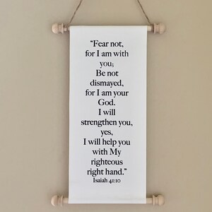 May include: White canvas scroll with black text that reads "Fear not, for I am with you; Be not dismayed, for I am your God. I will strengthen you, yes, I will help you with My righteous right hand." Isaiah 41:10. The scroll is hanging from a wall with a rope and wooden dowels.