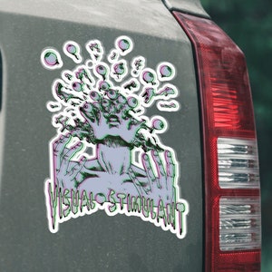 May include: A sticker on a car with a graphic of a person with multiple eyes and hands, with the text "VISUAL STIMULANT" below.