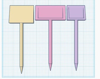 Puede incluir: Tres marcadores de plantas de madera con letreros de diferentes colores. El primer marcador tiene un letrero beige, el segundo marcador tiene un letrero rosa y el tercer marcador tiene un letrero morado.