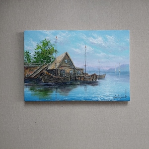 May include: A painting depicting a wooden house situated on a lake, with boats moored in front. The sky is blue with white clouds, and there are trees to the left of the painting.