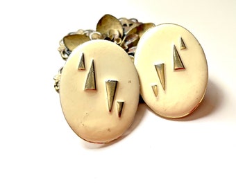 Off White round clip on earrings with gold tone etched designs