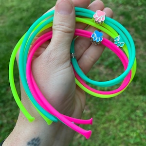May include: Four neon coloured silicone bracelets with paw print charms. The bracelets are green, yellow, pink and blue.