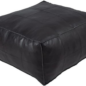 May include: Black leather ottoman with a square shape and a quilted design. The ottoman has a white stitching detail around the edges.