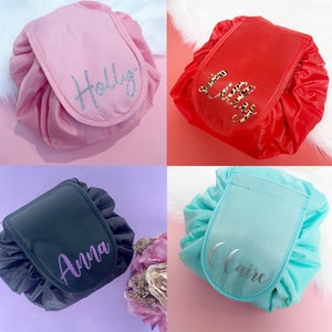 May include: Four drawstring makeup bags in different colors with personalized names: Holly, Lily, Anna, and Claire. The bags are made of a soft, silky fabric and have a small pocket on the front.