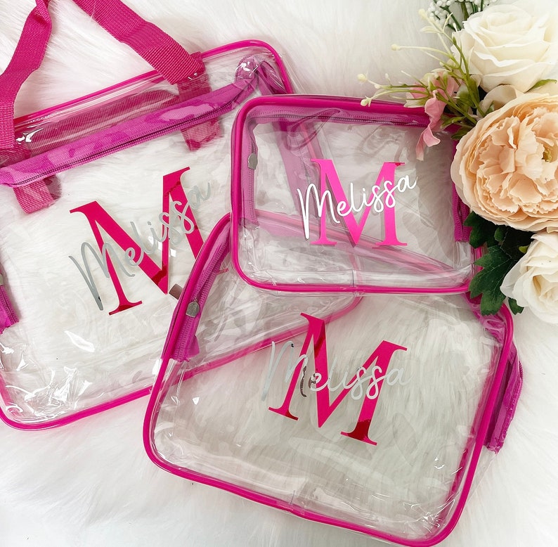 May include: Three clear plastic zippered bags with pink trim. Each bag has the name "Melissa" printed in silver with a large pink "M" in the center.