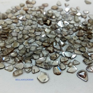 May include: A pile of rough, unpolished, brown diamonds, also known as raw diamonds. The diamonds are various shapes and sizes, with some having a slight iridescent sheen.