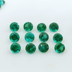 May include: A collection of 12 round, green gemstones. The gemstones are faceted and have a bright, shiny finish.