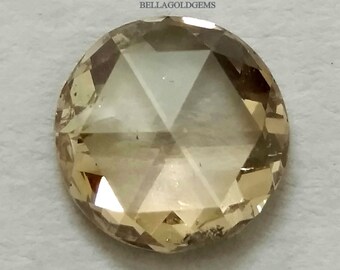 May include: A round, faceted, light brown gemstone with a slightly cloudy appearance. BELLAGOLDGEMS is printed in the top left corner of the image.