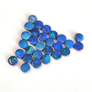 May include: A collection of round, cabochon-cut blue opals arranged in a triangular formation. Each gemstone displays a vibrant play-of-colour with flashes of bright green and electric blue, set against a smooth, polished surface finish.