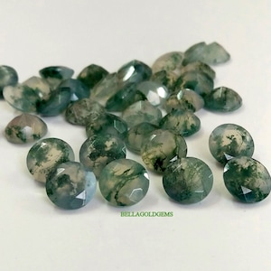 Può includere: Una collezione di 20 cabochon di agata muschiata verde, ognuno con un motivo unico di verde e bianco. Le pietre sono lisce e lucidate, e hanno un aspetto leggermente traslucido.