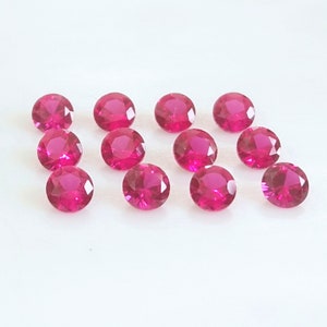 May include: Twelve round, faceted, pink gemstones. The gemstones are arranged in two rows of six.