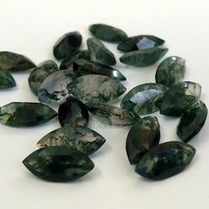 May include: A collection of green moss agate gemstones, cut into marquise shapes. The stones have a variety of green and white patterns.