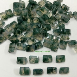 Op de afbeelding: Een grote stapel groene mosagaat edelstenen in een rechthoekige vorm. Er zijn 12 kleinere mosagaat edelstenen in de onderste rij van de afbeelding.