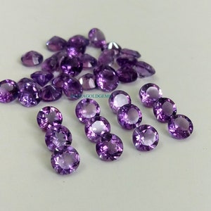 Puede incluir: Un grupo de 25 piedras preciosas de amatista redondas y moradas, con 8 piedras preciosas adicionales dispuestas en tres filas.