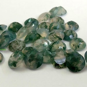 Puede incluir: Una colección de cabujones de ágata musgosa en varios tonos de verde y blanco. Las piedras son de forma ovalada y tienen un acabado liso y pulido.