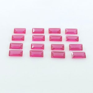 Puede incluir: Una colección de 15 piedras preciosas rectangulares de color rosa, dispuestas en filas sobre una superficie blanca.