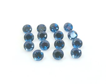 May include: A collection of 14 round, blue gemstones. The gemstones are arranged in rows on a white surface.